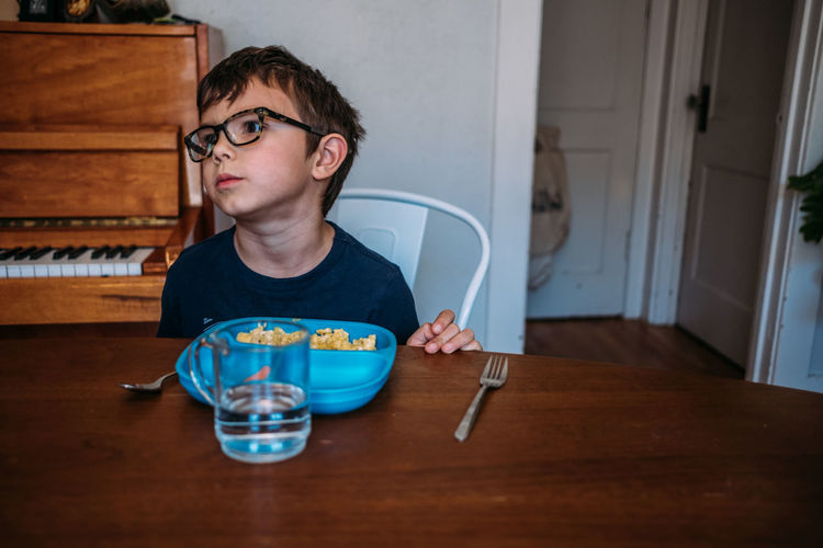 Young boy looking annoyed at the table during a meal