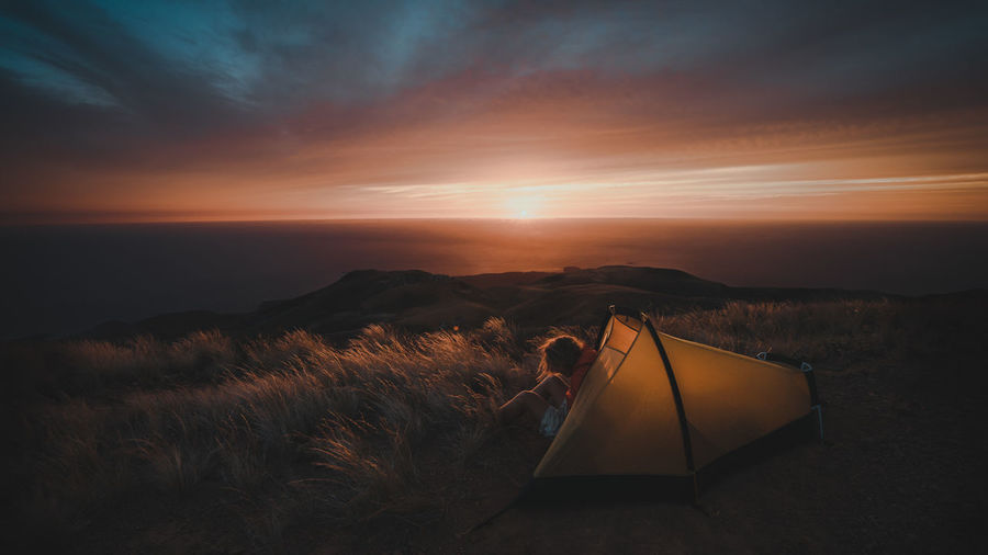 Man sitting in tent during sunset