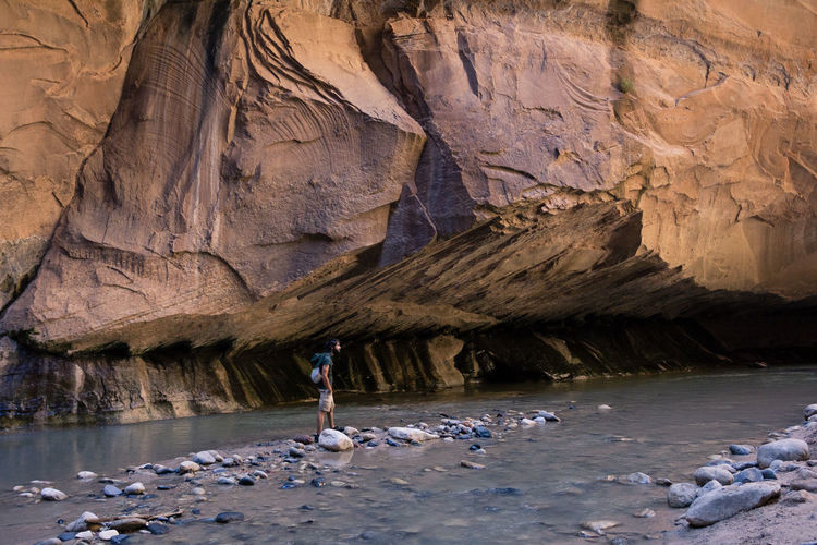 Mid distance view of man standing on rocks in river at zion national park