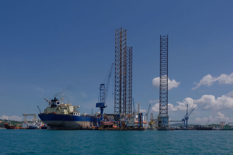 Cranes at commercial dock against blue sky