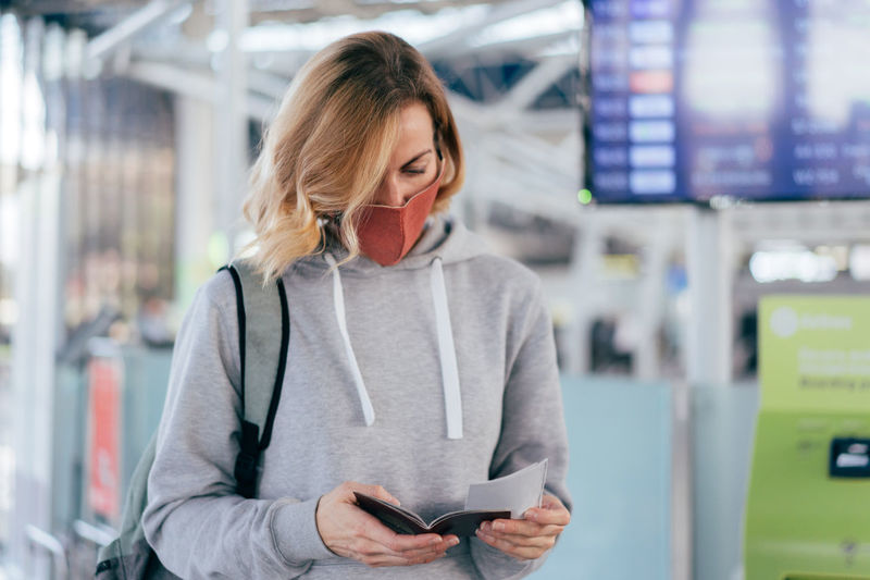 Woman wearing mask holding passport at airport