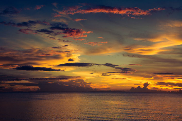 Scenic view of sea against dramatic sky during sunset