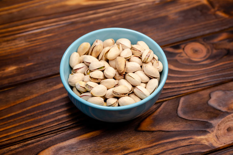 Pistachio in a blue dish on a wooden background