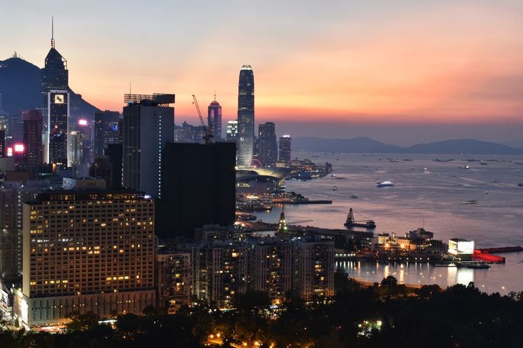 Illuminated buildings in city against sky during sunset