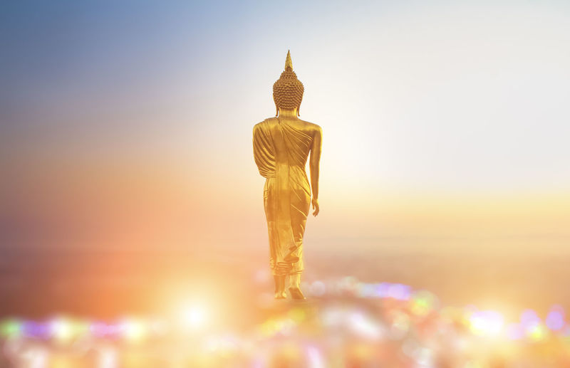 Statue of buddha against sky at sunset