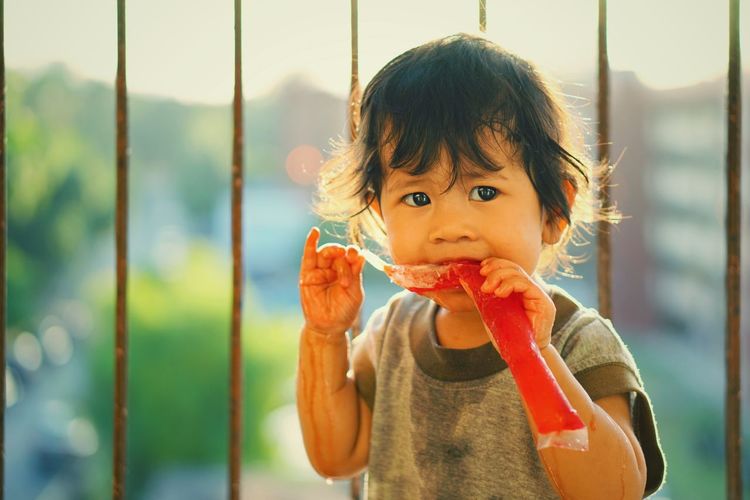 Close-up of baby girl having frozen food against railing
