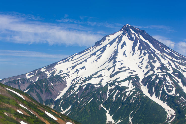 Volcano viluchinsky covered with snow at sunny summer day, the kamchatka peninsula.