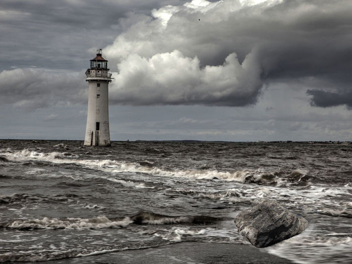 Lighthouse in sea against sky