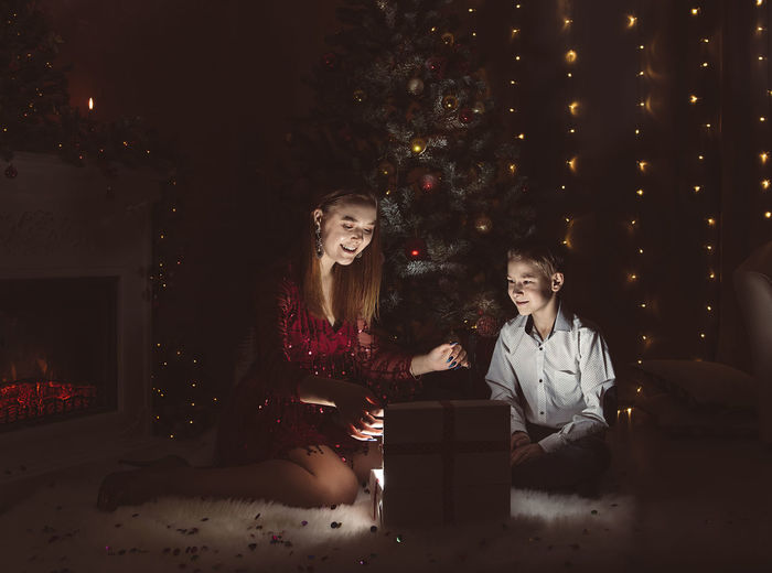Two people sitting in illuminated christmas tree at night
