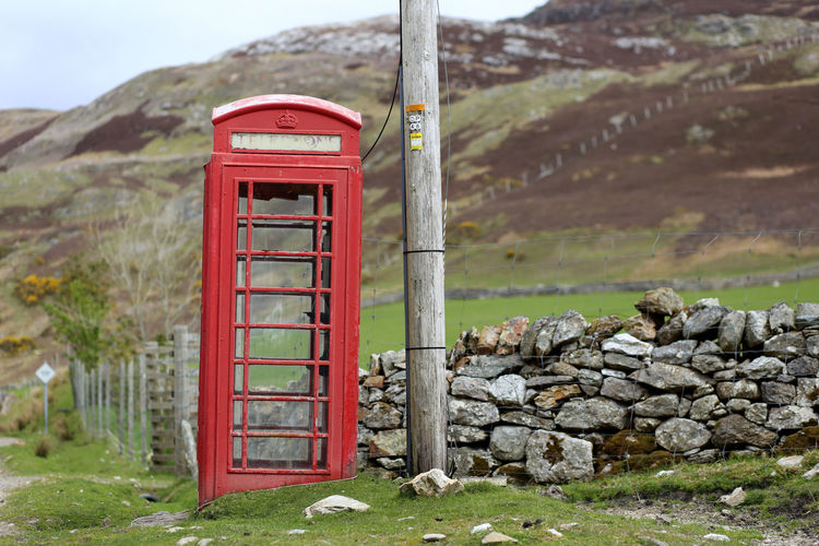 Close-up of telephone booth by mountain against sky