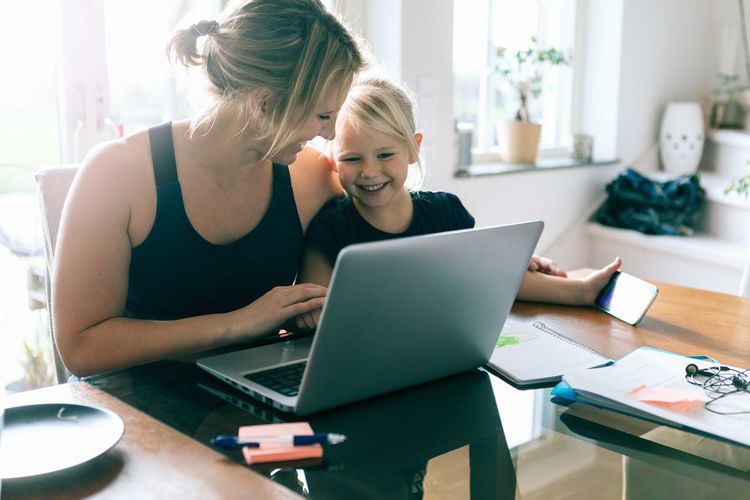 Daughter looking at laptop while sitting by mother at home