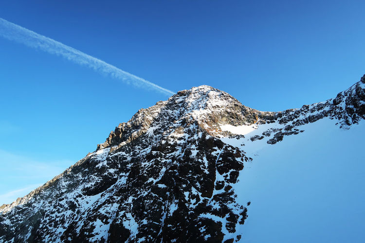 Cloud trail over a snow-capped peak