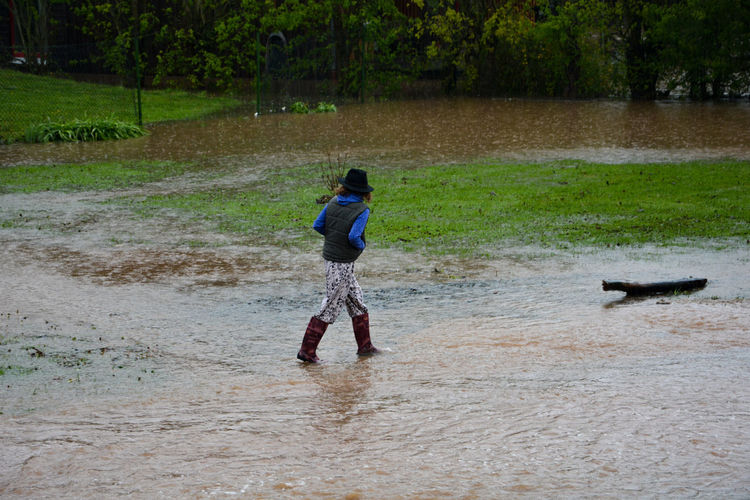 Rear view of a girl walking in water by flood 