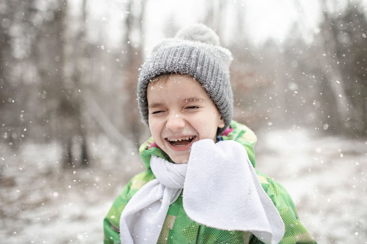 Portrait of laughing boy standing outdoors during winter