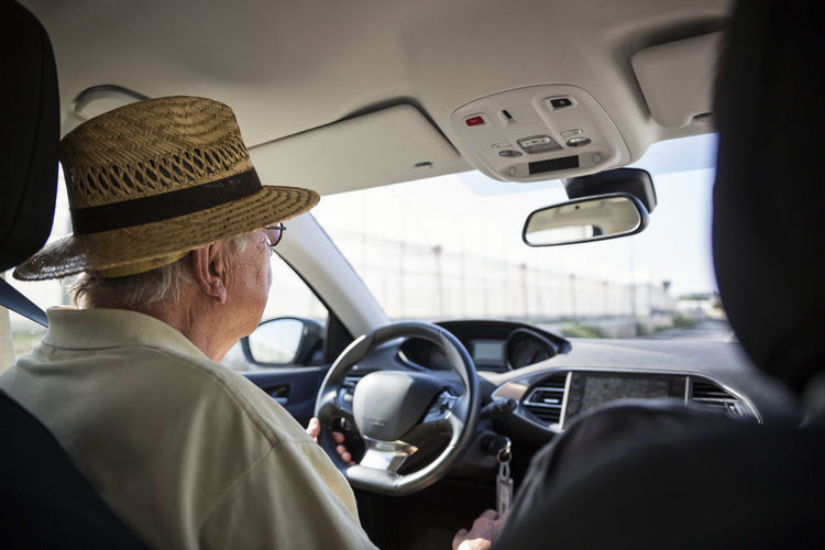 Sicily, ragusa, senior man with straw hat driving car