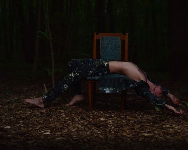 Man lying on chair in forest