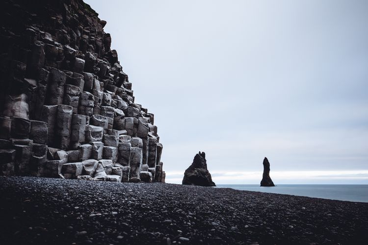 Rock formations on beach against sky