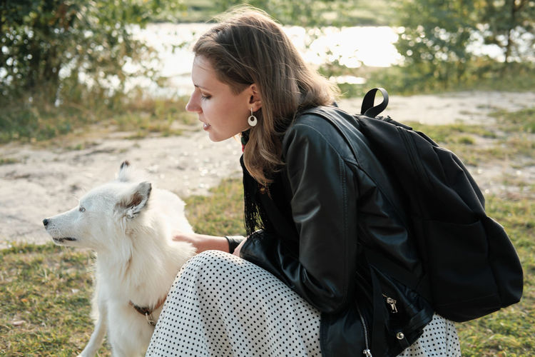 Happy woman hugging and stroking her dog. yakutian laika looking aside. animal friends, outdoors