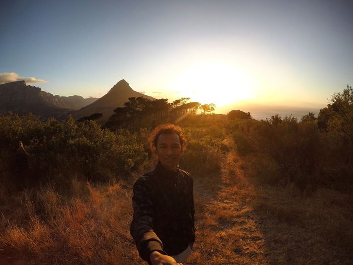 Portrait of man standing on field against sky during sunset