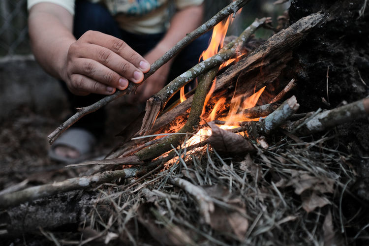 Close up view of a hand lighting up a fire while camping in the forest