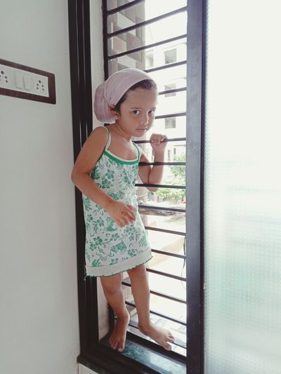Cute girl standing by window at home