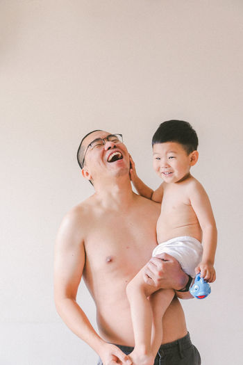 Full length of shirtless man with baby