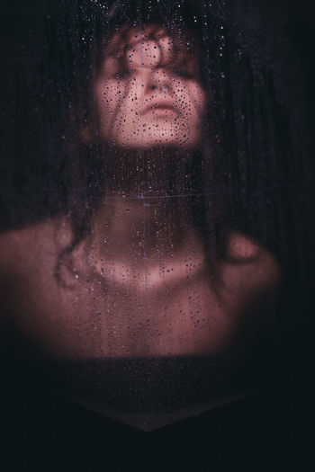 Portrait of woman in wet glass