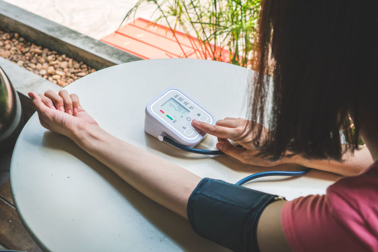 Midsection of woman checking blood pressure on table