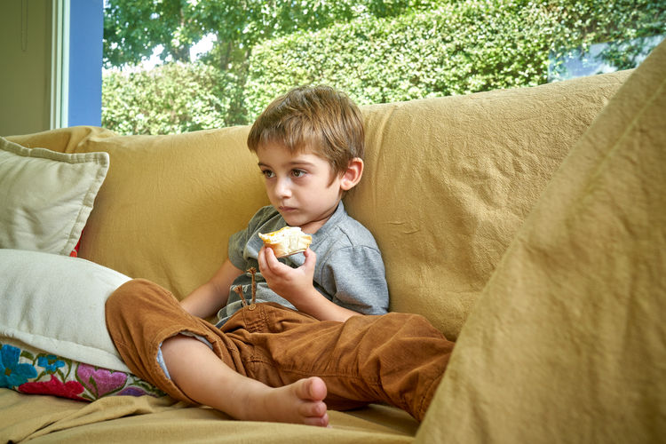 Side view of boy sitting on sofa at home