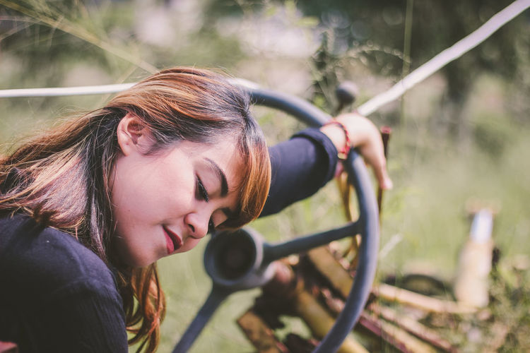 Close-up of beautiful young woman leaning on steering wheel