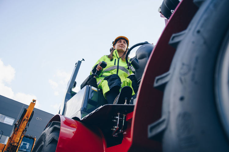 Woman driving construction vehicle against sky