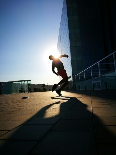 Silhouette men dancing on footpath against sky