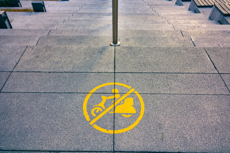 High angle view of yellow arrow symbol on footpath