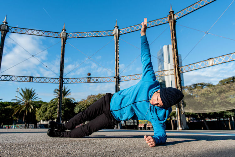 Full body of determined sportive male in activewear performing side plank exercise while training muscles during outdoor fitness workout