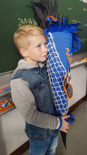 Boy looking away while holding decoration on floor