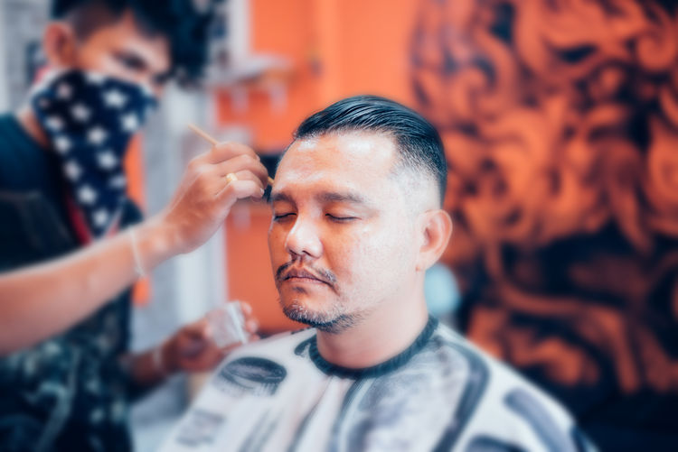 Hair stylist dyeing hair of man at salon