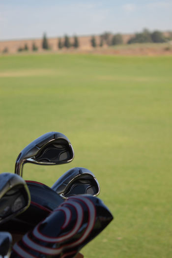 Close-up of golf clubs overlooking lucious green  golf course 