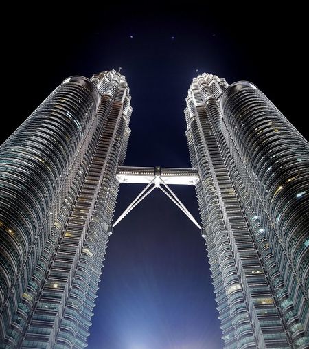Low angle view of illuminated petronas towers against sky at night