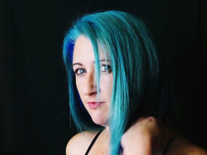 Portrait of beautiful woman with dyed hair against black background