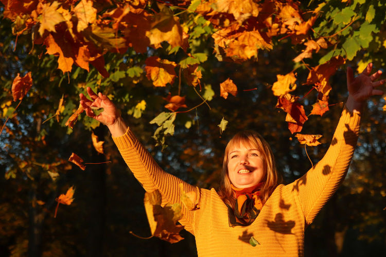 Hello autumn. happy blonde elegant 40 year old woman in yellow pullover, shawl outside in the autumn 