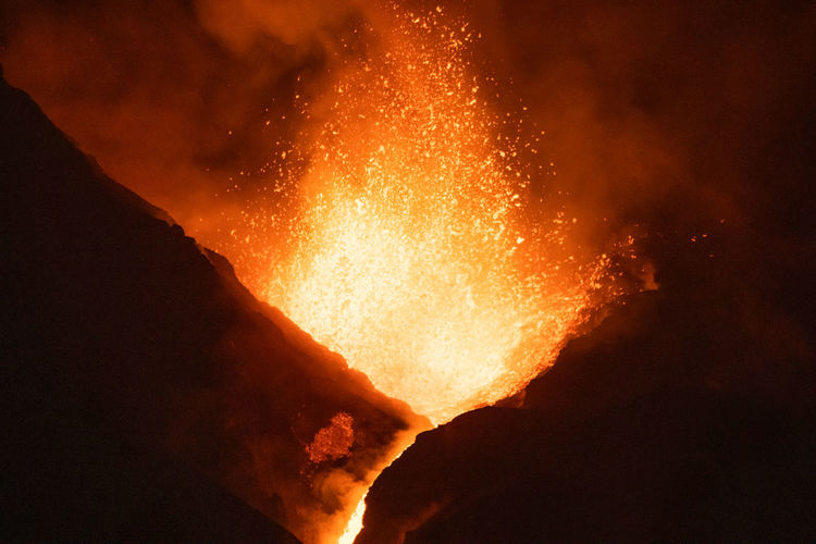 Hot lava and magma pouring out of the crater at night. cumbre vieja volcanic eruption in la palma canary islands, spain, 2021