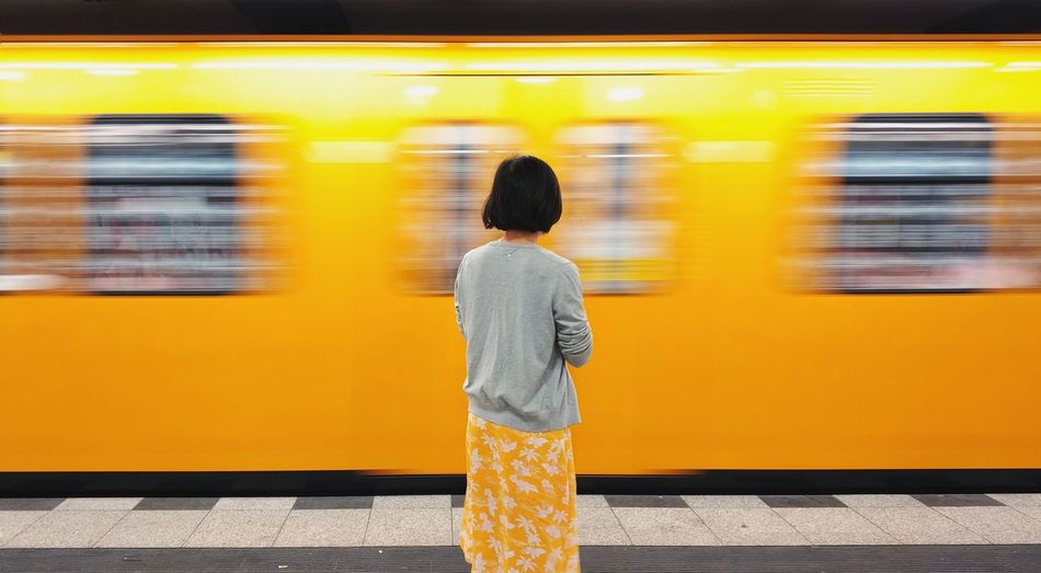 Rear view of woman standing at railroad station