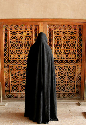 Woman in burka standing against door