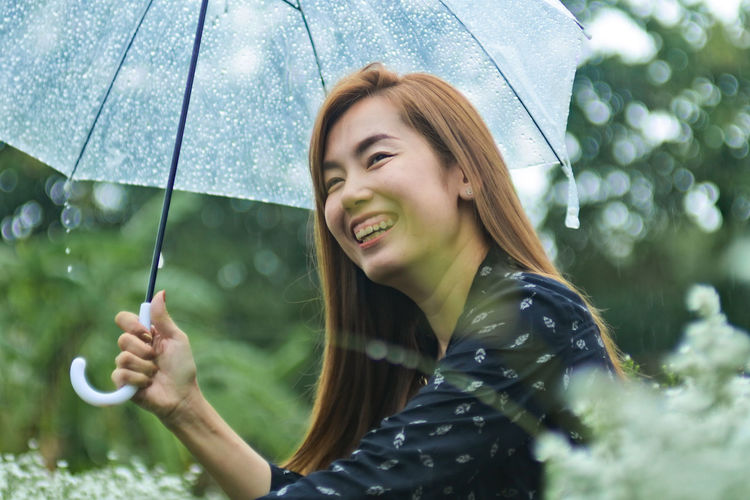 Portrait of woman holding wet umbrella during rainy season