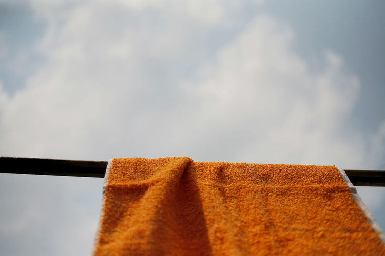 Close-up of clothes drying on rope against sky