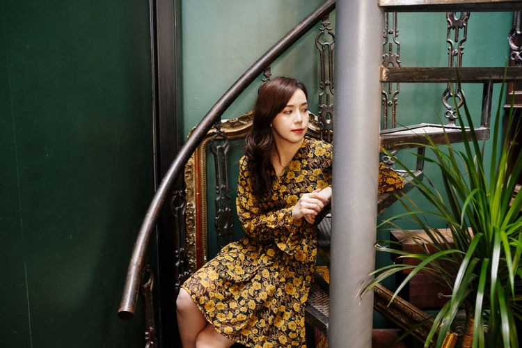 Woman looking away while standing on railing