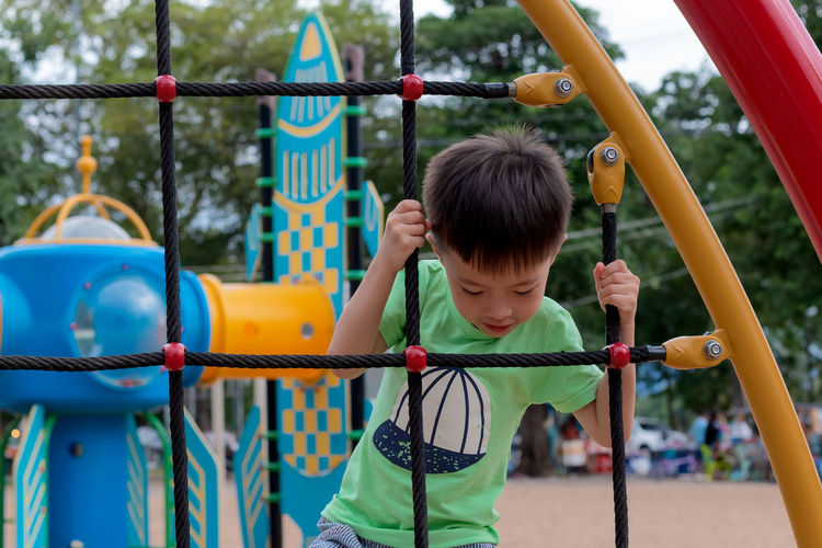 Boy climbing on rope ladder at playground