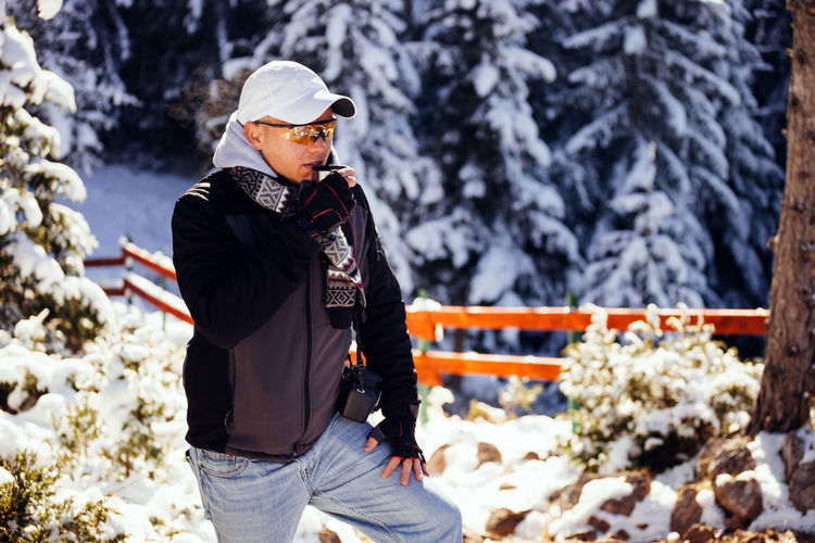Man standing against snow covered trees