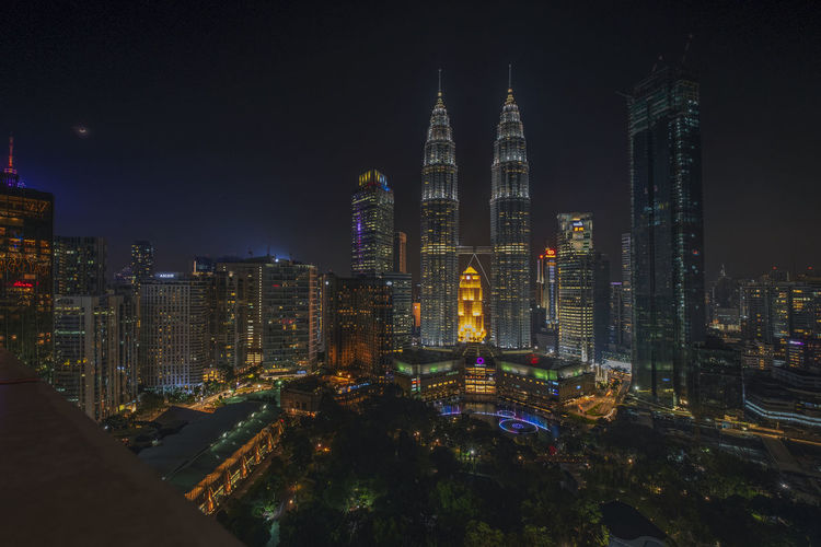 Petronas towers in city against sky at night