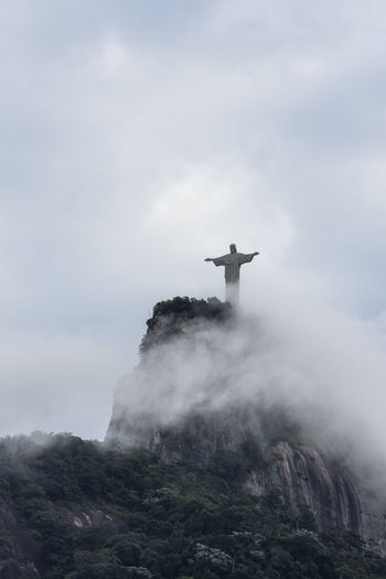 Low angle view of statue on mountain against cloudy sky